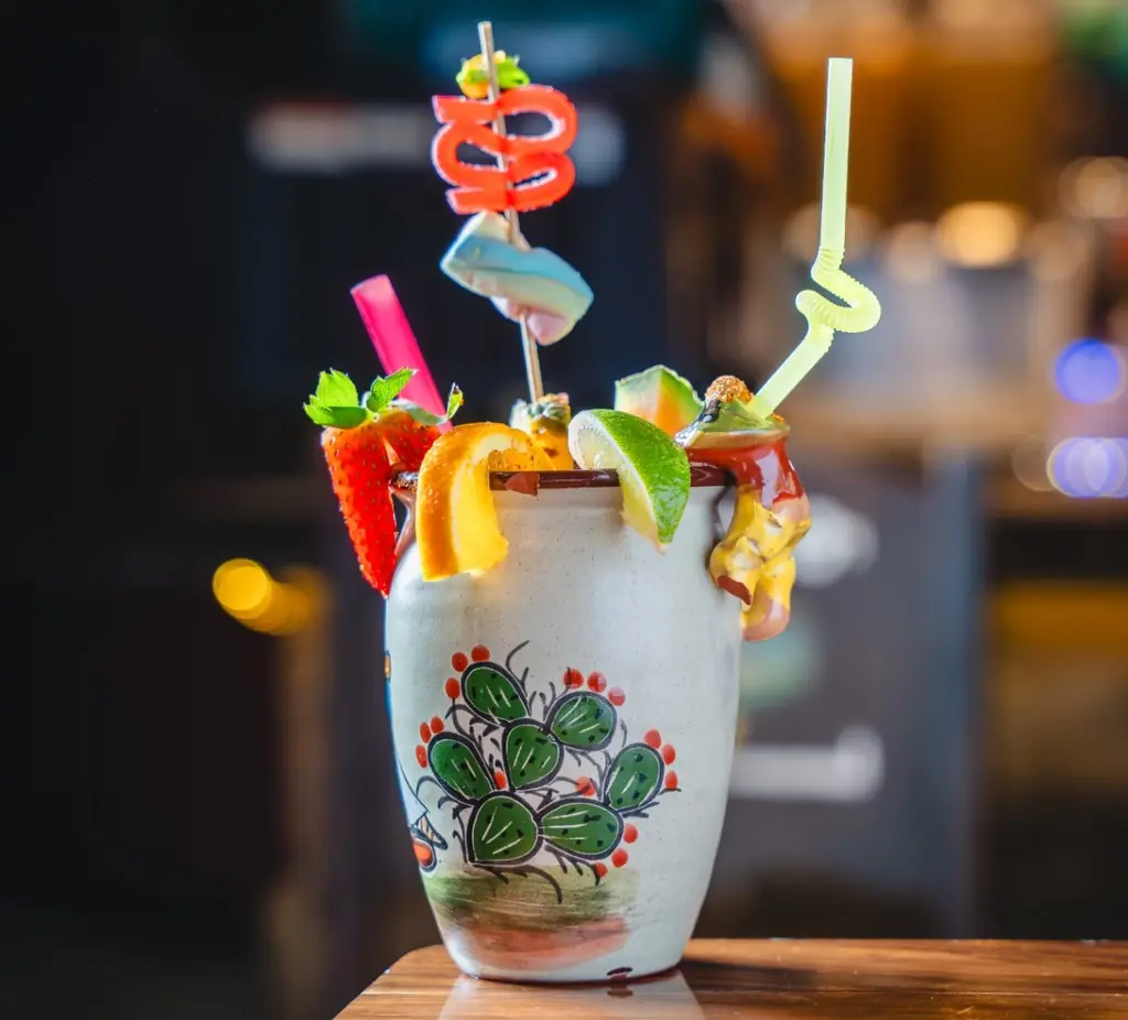 A cantarito cocktail loaded with fruit and candy straws